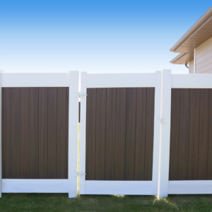 A close-up view of a two-tone privacy fence with a gate, featuring white posts and brown panels, by Performance Fencing in Rigby, ID.