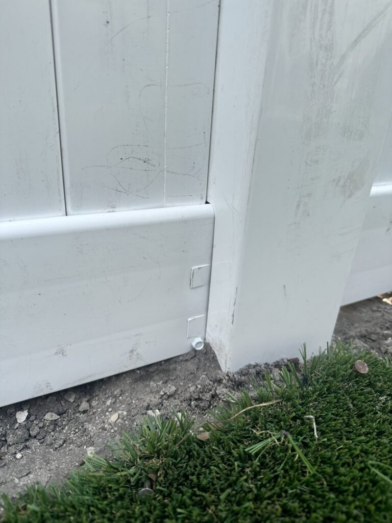 A close-up view of the base of a white vinyl fence post installed by Santis Fence & Home Service in Tampa Heights, FL