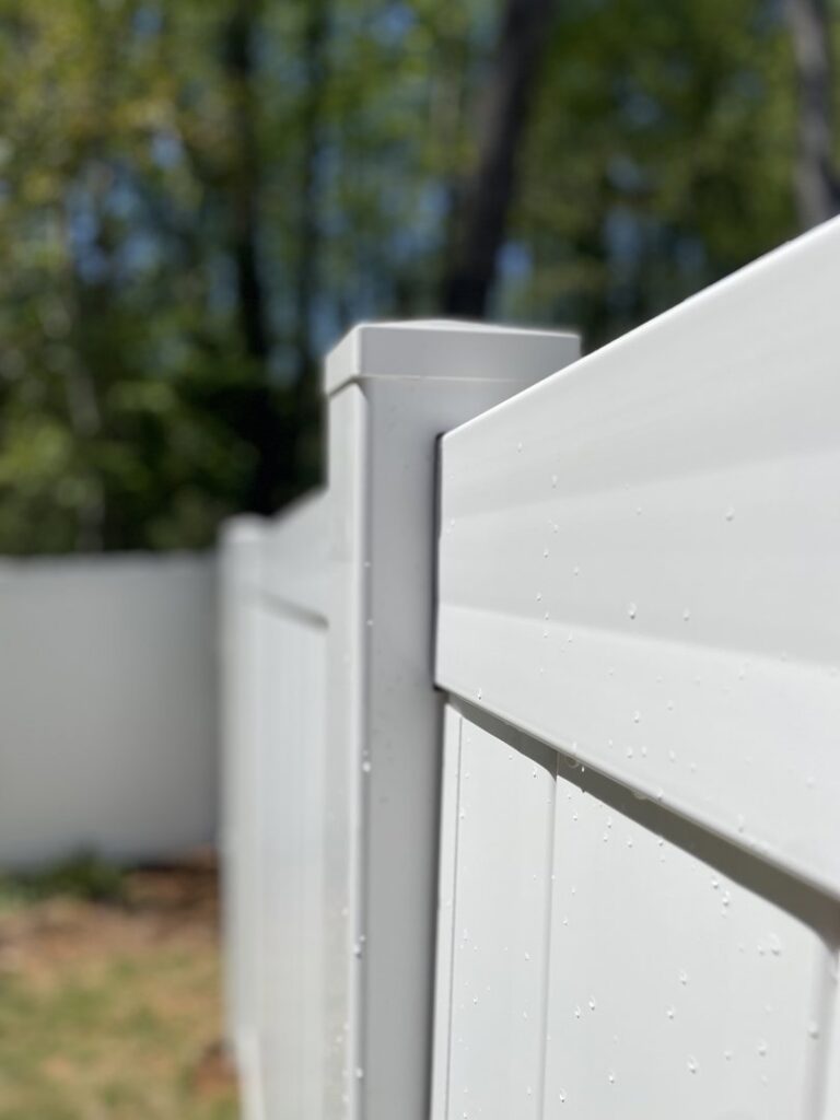 A close-up view of a white vinyl fence post and panel, showcasing quality installation by RDU Fence in Holly Springs, NC.