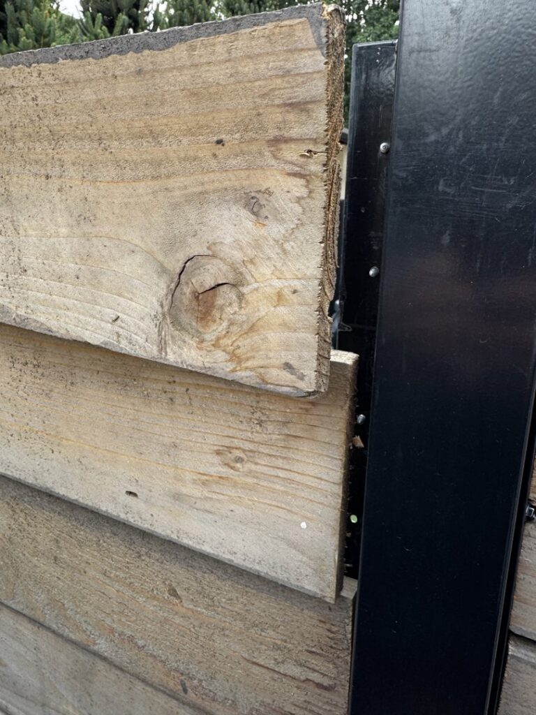 A close-up view of a wooden fence panel securely attached to a black metal post by First Rate Fence & Supply in Denver, CO.