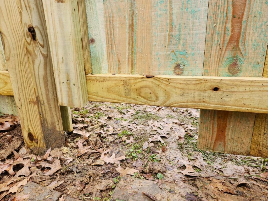 A close-up view of the base of a newly installed wooden fence post by Fenceworks of Middle Tennessee in Nashville, TN.