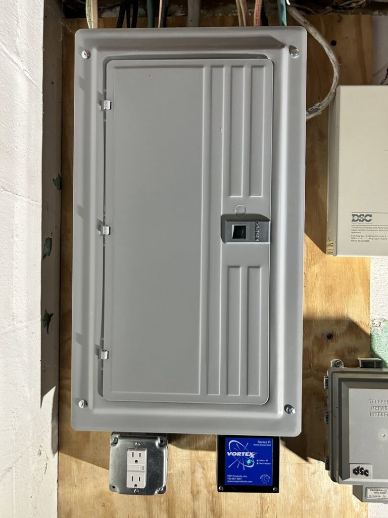 A newly installed and closed electrical panel with a Surge Electric LLC sticker and an adjacent outlet in Youngstown, OH.