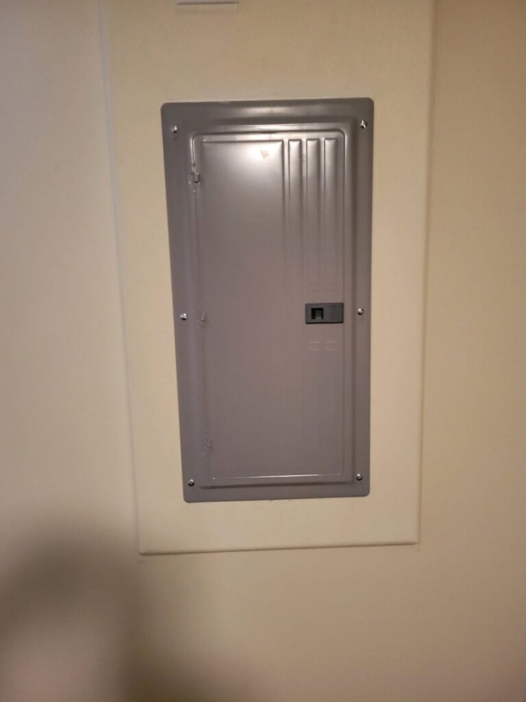 A closed electrical panel installed on an interior wall by Interstate Electrical Contractors in Dalton Gardens, ID.