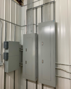 Neatly installed closed electrical panels and conduits on a wall by Tallent Electrical Services in Tulsa, OK