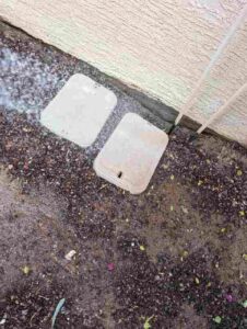 Two closed pest bait stations placed discreetly next to a house wall, used for rodent control by Bernard's Pest in Glendale, AZ.