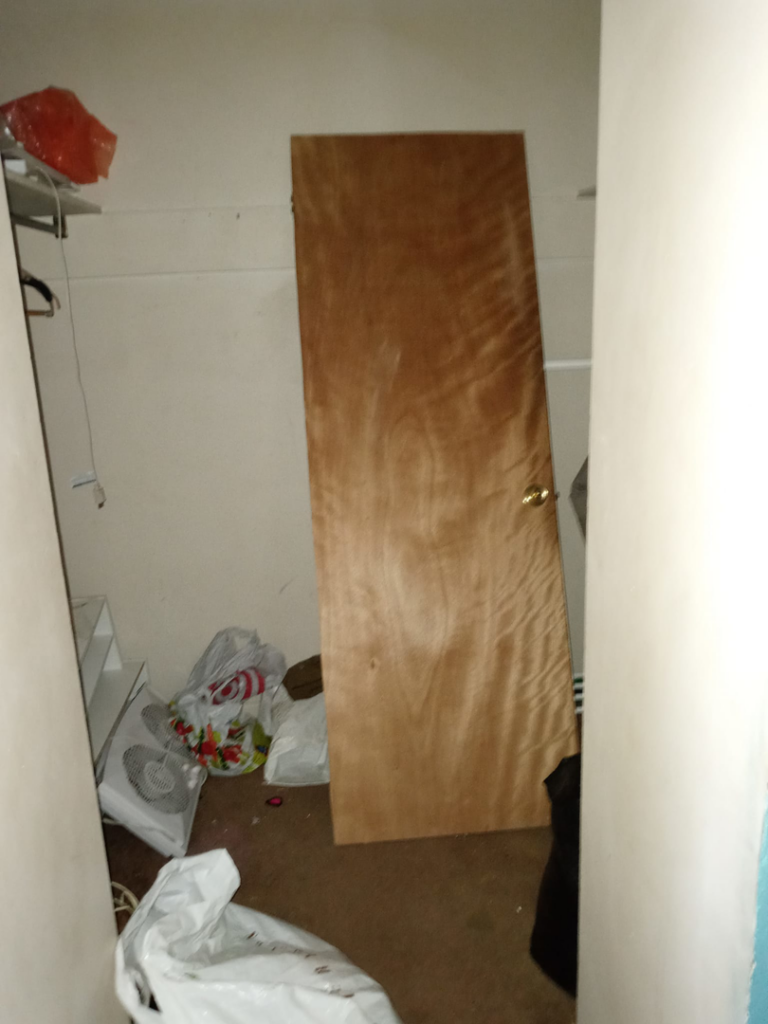 A cluttered hallway with worn brown carpet, awaiting new carpet installation from Stubborn Bull Contracting in Pittsburgh, PA.