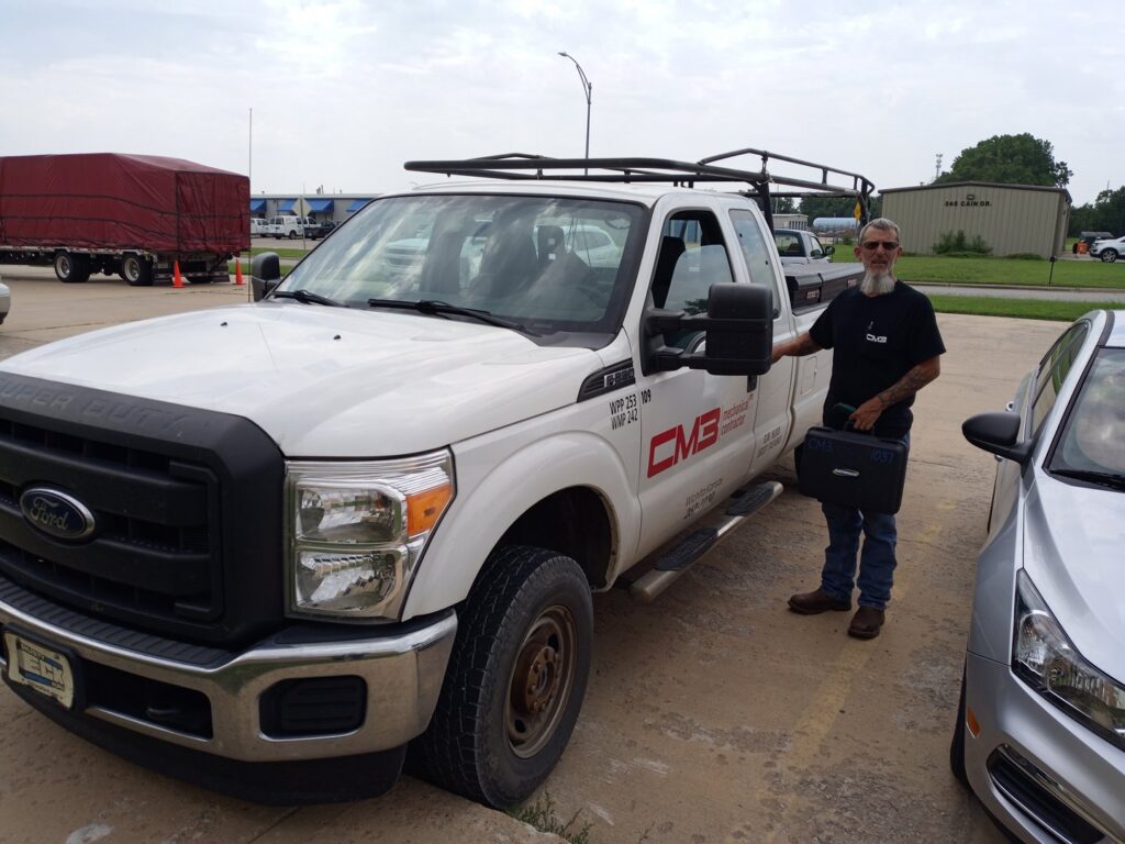 A CM3, Inc. HVAC technician standing proudly next to a company service truck in Wichita, KS.