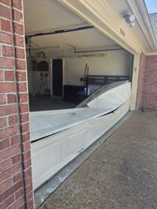 A severely damaged and collapsed white garage door requiring service from The Garage Man in Memphis, TN.