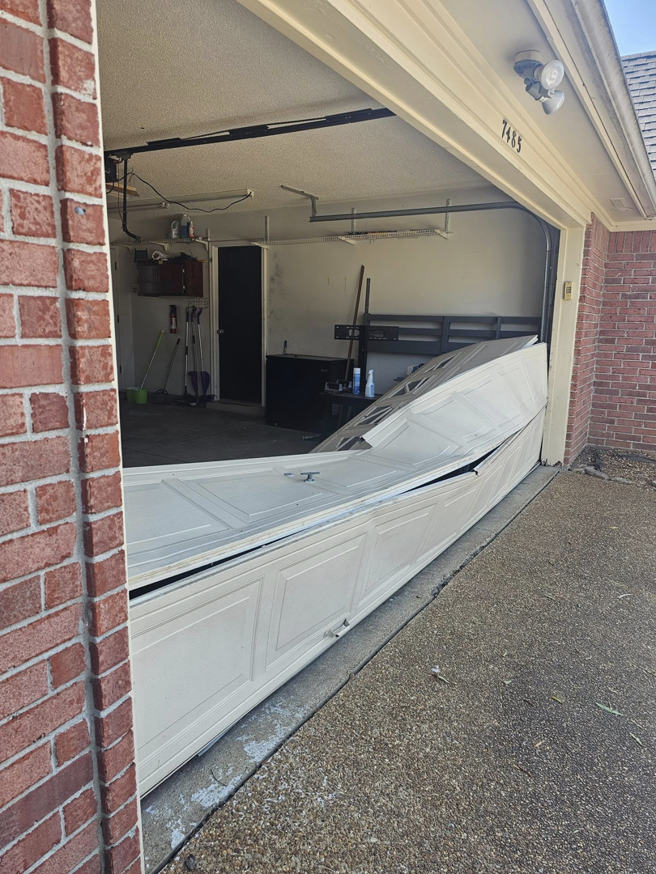 A severely damaged and collapsed white garage door requiring service from The Garage Man in Memphis, TN.