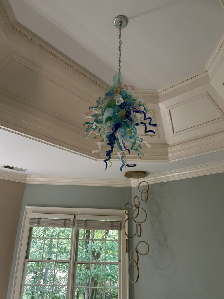 Installation of a colorful glass chandelier and a modern ring pendant light by Perfection Lighting, Design, and Installations in Atlanta, GA.