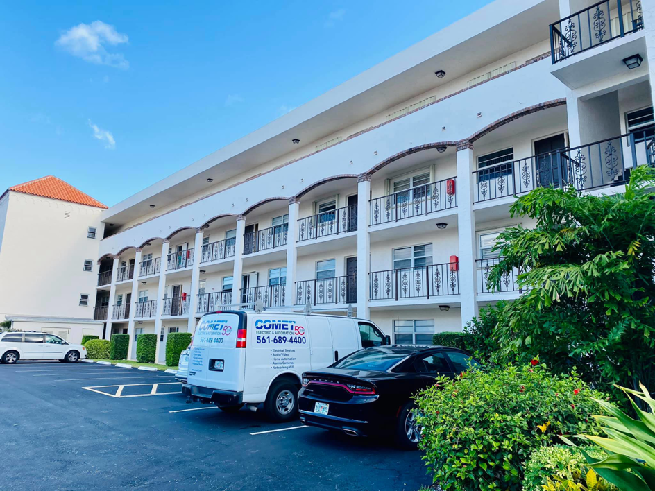 A Comet Electric service van parked outside a residential building for an electrician job in West Palm Beach, FL.