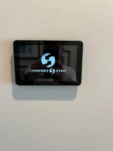 A Comfort Sync smart thermostat installed on a wall by Comfort Zone AC and Heating Services LLC in Sunrise Beach, MO