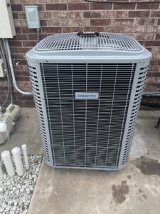 A Comfortmaker outdoor AC unit installed next to a brick wall, showcasing quality work by Rhino Heating and Air Conditioning LLC in Norman, OK.
