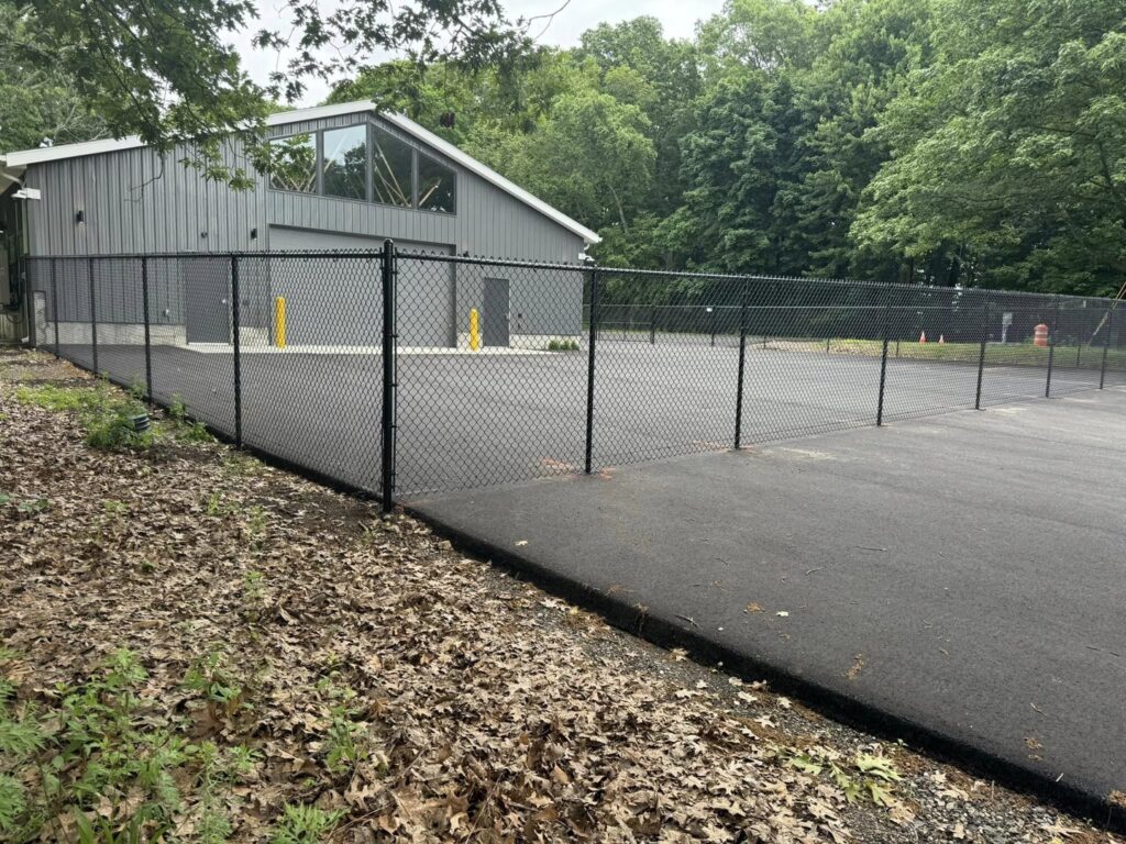 A commercial black chain link fence installed around a building by Select Fence & Guardrail in North Haven, CT.