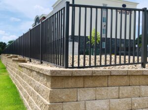 A commercial black metal fence on a retaining wall by American Fence Company of Columbus in Grand Island, NE.