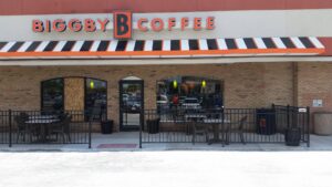 A commercial black metal fence enclosing an outdoor seating area at a coffee shop, installed by Sharper Image Fence in Fort Wayne, IN.