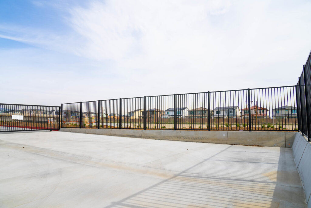 A black metal fence and gate installed in a commercial or industrial area by Competitive Fence Contractors LLC in Scottsdale, AZ.