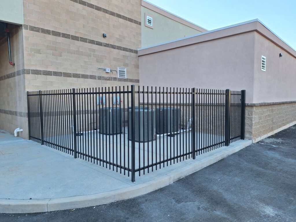 A black metal fence enclosing HVAC units next to a commercial building by Competitive Fence Contractors LLC in Scottsdale, AZ.