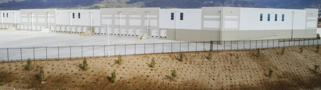 A long black metal fence installed in front of a large commercial building by Competitive Fence Contractors LLC in Scottsdale, AZ.