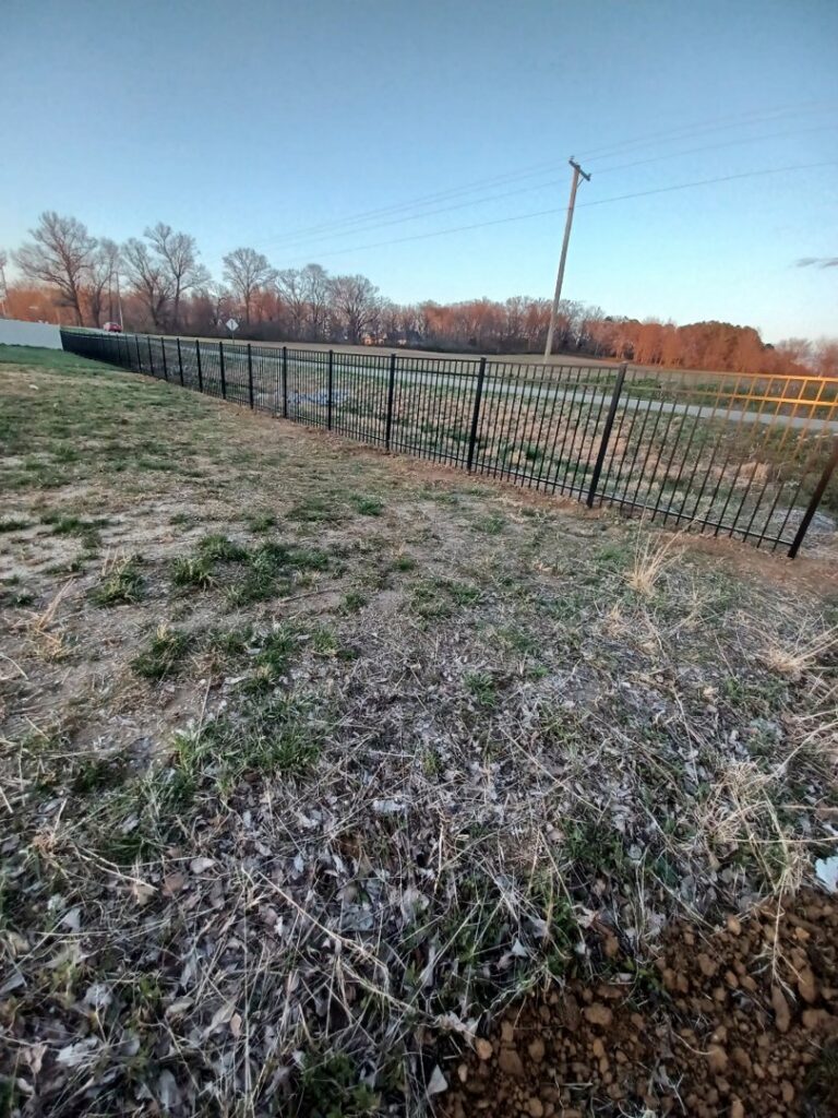 A long black ornamental metal fence installed along a roadside or commercial property by Nailed It Fencing and Exteriors in Evansville, IN.