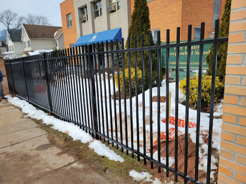 A commercial black metal picket fence installed along a building, showcasing work by Fox Fence Enterprises Inc in Clifton, NJ.