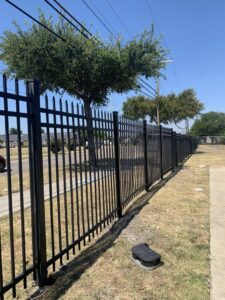 A long commercial black metal security fence with spiked tops installed by Craftsman Automatic Gates in Dallas, TX.