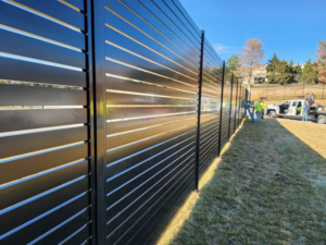 A long commercial black slatted fence being installed by Van's Fence in Kansas City, MO.