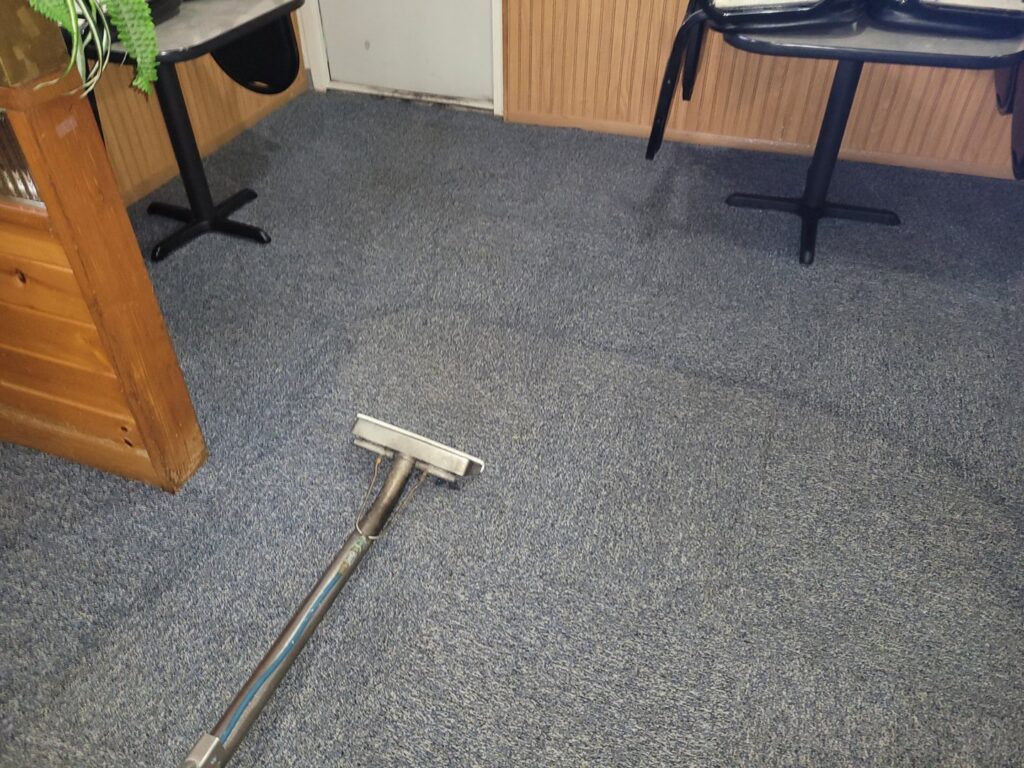 A carpet cleaning tool on a blue commercial carpet, showing a job in progress by Mr. Suds Carpet Cleaning LLC in Coeur d'Alene, ID.