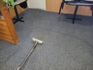 A carpet cleaning tool on a blue commercial carpet, showing a job in progress by Mr. Suds Carpet Cleaning LLC in Coeur d'Alene, ID.