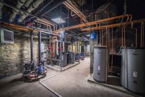 A commercial boiler room with extensive piping and water heaters, representing HVAC and mechanical systems by DMC Service, Inc. in Olathe, KS.