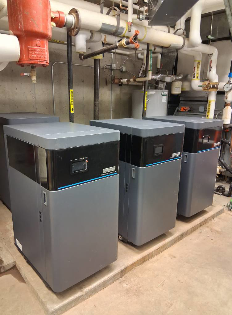 Three commercial boilers or water heaters installed in a mechanical room by High Standard HVAC LLC in Cheyenne, WY.