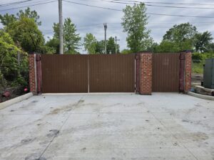 A large commercial brown privacy gate with brick pillars installed by Affordable Fence Builders in Dayton, OH.