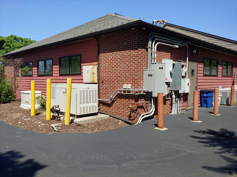 Exterior view of a commercial building showing electrical panels and conduit installed by 2 Live Wires in Slatington, PA.