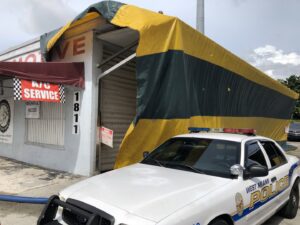 A commercial building covered in a yellow and green striped tarp for fumigation by Globe Pest Inc in Miami, FL.