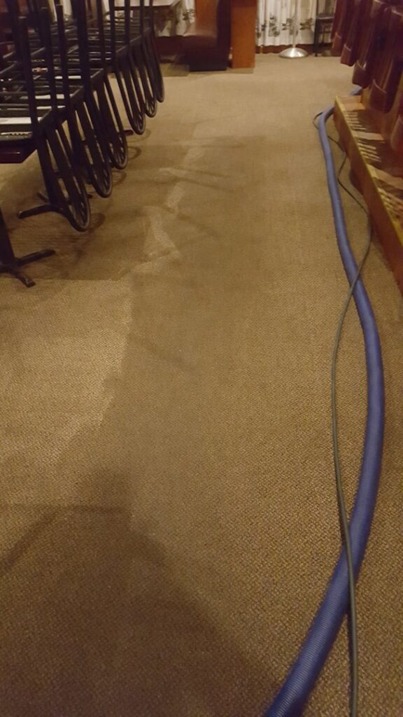 Commercial carpet cleaning in a restaurant with cleaning equipment, showing a clean and dirty section, by Keith's Cleaning Service in Auburn, ME