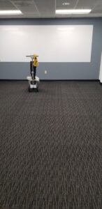 A commercial carpet cleaning machine positioned in an office space with dark patterned carpet by Steam Giant in Raleigh, NC.