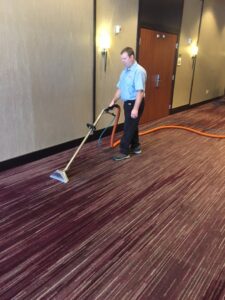 A technician performing commercial carpet cleaning in a hallway for Complete Carpet Care in Fort Wayne, IN.