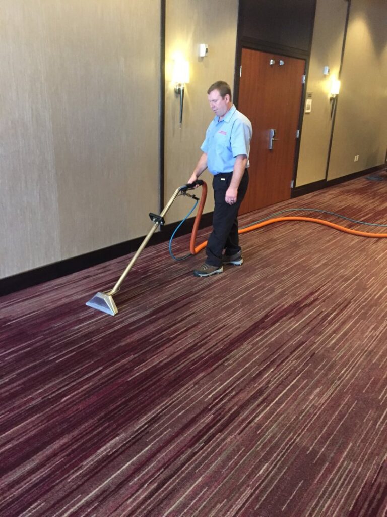 A technician performing commercial carpet cleaning in a hallway for Complete Carpet Care in Fort Wayne, IN.