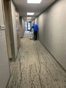 A professional cleaning a commercial hallway carpet with a machine by Elite Clean Steamers in Indianapolis, IN