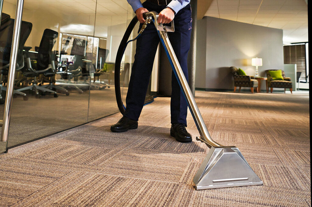 A professional performing commercial carpet cleaning in an office building by Howells Carpet Cleaning in Milwaukie, OR.