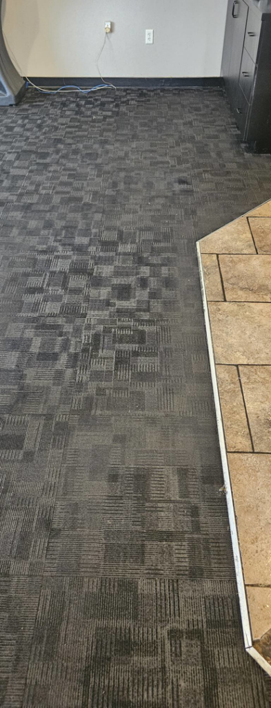 Commercial patterned carpet showing cleaning in progress next to tile by American Carpet Care, Inc. in Watertown, SD.