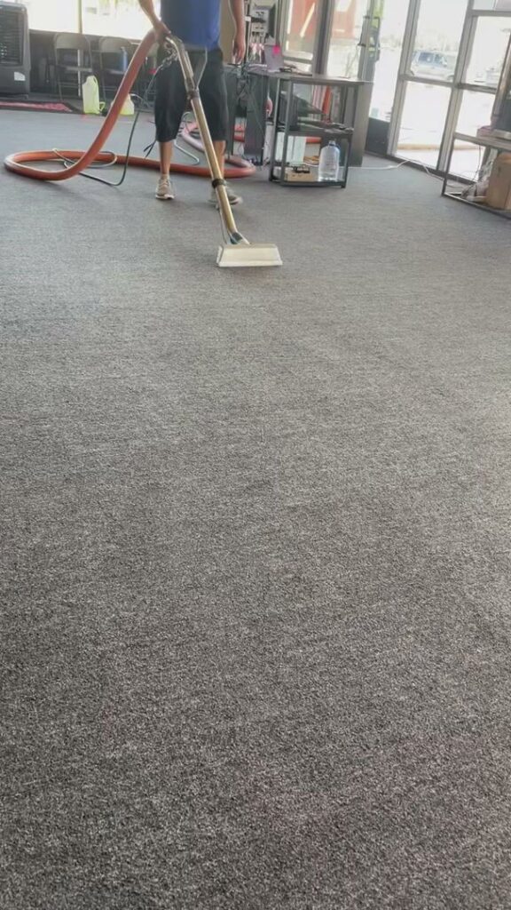 A professional performing commercial carpet cleaning with a machine on a grey carpet by Specialty Carpet Care in Surprise, AZ