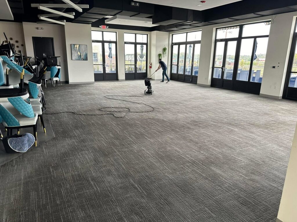 A worker cleaning a large commercial carpeted area with a floor machine for Great Day Carpet & Tile Cleaning LLC Desoto in Olive Branch, MS.