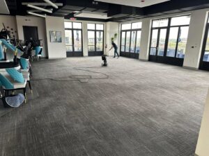 A worker cleaning a large commercial carpeted area with a floor machine for Great Day Carpet & Tile Cleaning LLC Desoto in Olive Branch, MS.