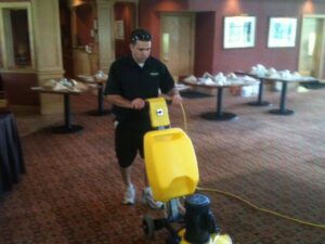 A technician operating a commercial rotary carpet cleaning machine on a patterned carpet for Steam Giant in Raleigh, NC.