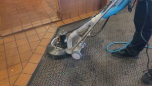 A professional operating a carpet cleaning machine on a patterned commercial carpet by Mr. Suds Carpet Cleaning LLC in Coeur d'Alene, ID.