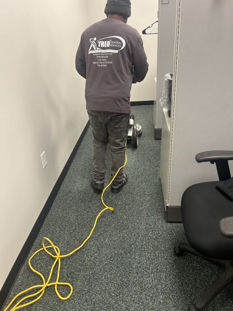 A professional performing commercial carpet cleaning in an office by Treo General Services of North Carolina LLC in Durham, NC.