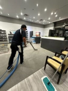 A technician performing commercial carpet cleaning in a business setting by Precise Carpet Care in Albuquerque, NM.