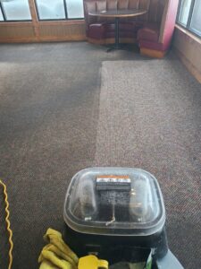 Commercial carpet cleaning in progress at a restaurant, showing a clean/dirty divide by Alaska Floor Care Specialists in Fairbanks, AK.