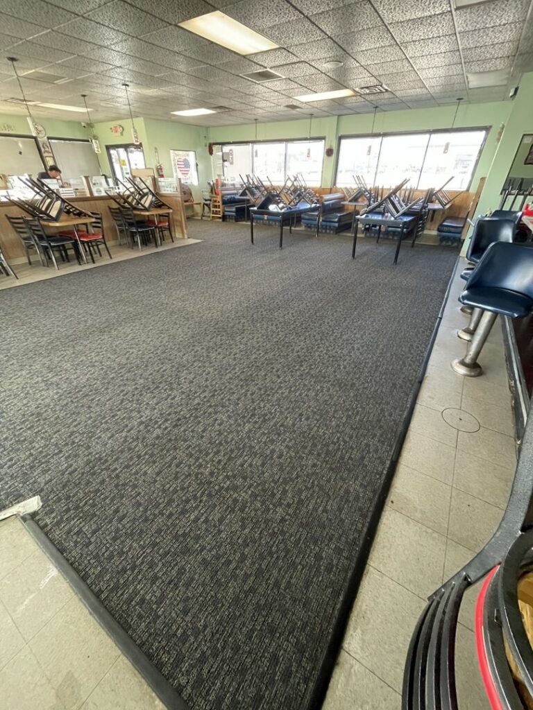 A clean commercial carpet in a restaurant setting with stacked chairs, professionally maintained by Carpet PRO Cleaner in Cary, NC.